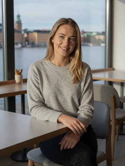 Astrid, 27, Swedish woman with blonde hair smiling at a Stockholm cafe with soft winter light