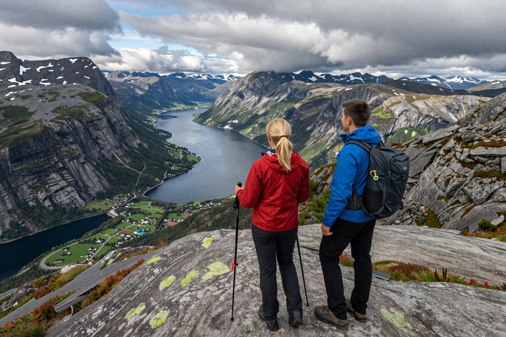 Couple hiking in Norwegian mountains with panoramic fjord view from summit