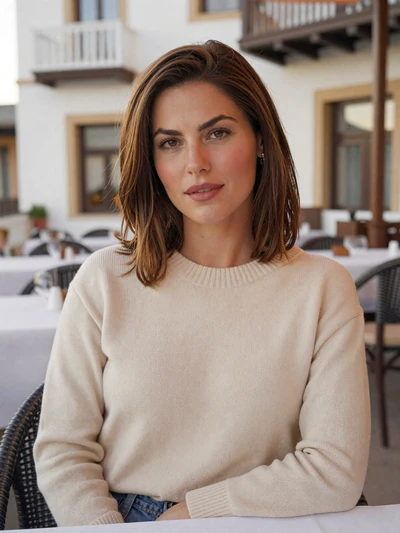 Katerina, 33, a Cypriot woman at an outdoor restaurant with Mediterranean architecture behind her