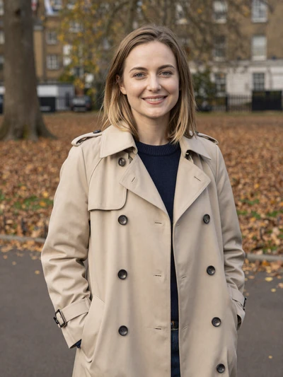 Emily, 27, a friendly British woman with brown hair smiling in a London park
