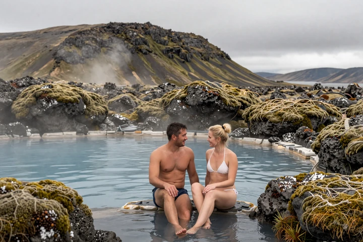 Couple relaxing together in a natural Icelandic hot spring surrounded by volcanic landscape and steam