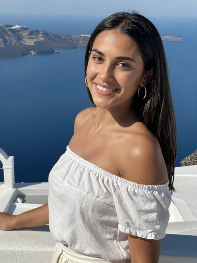 Eleni, 31, a radiant Greek woman on a terrace overlooking the Aegean Sea