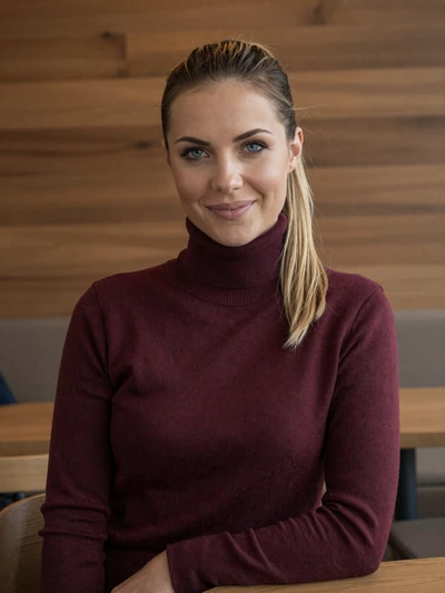 Katrin, 27, a German woman with blonde hair smiling confidently at a Munich cafe